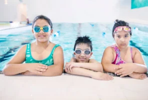 Three smiling children in swimwear - Credits: pexels