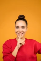 Young woman smiling with finger - Credits: pexels