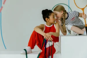 Two young girls whispering together, - Credits: pexels
