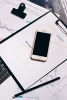 Smartphone resting on financial charts - Credits: pexels