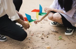 Adults kneeling on sand, engaging - Credits: pexels