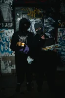 Two masked figures in a - Credits: pexels