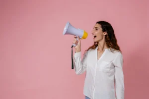 Confident woman using a megaphone - Credits: pexels