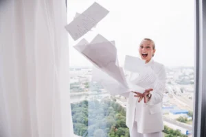 Businesswoman celebrating by tossing papers - Credits: pexels