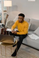 Man in yellow sweater composing - Credits: pexels