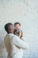 Affectionate father holding smiling baby - Credits: pexels