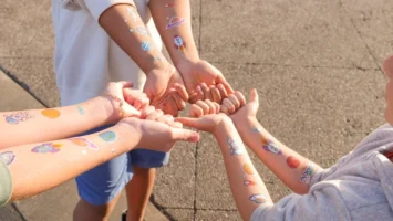 Children displaying space-themed temporary tattoos - Credits: pexels