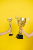 Two hands holding trophies against - Credits: pexels