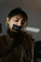 Distressed woman with 'HELP' on - Credits: pexels