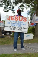 A man holding a Jesus-themed - Credits: pexels